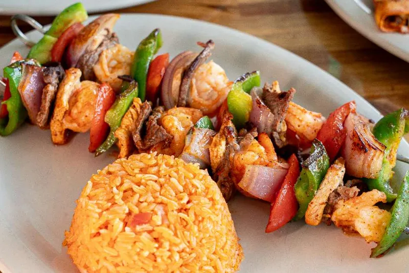 Grilled shrimp skewers with peppers, onions and rice at Guads
