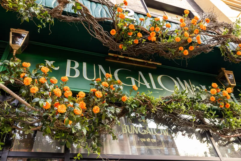 Marigold-draped green storefront and gold Bungalow signage at Bungalow in New York