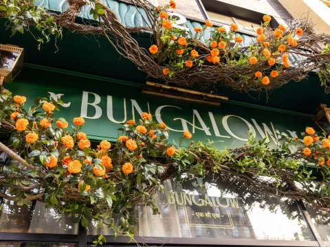 Marigold-draped green storefront and gold Bungalow signage at Bungalow in New York