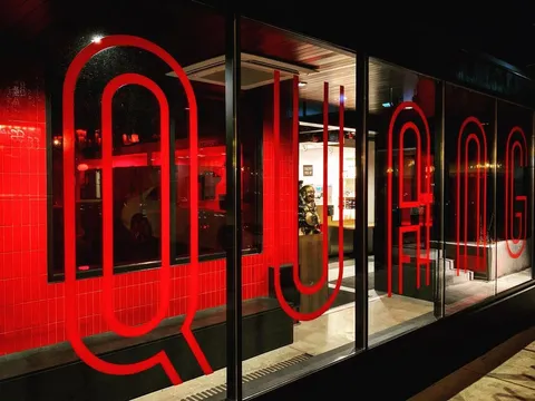 Nighttime storefront of Quang Restaurant at 2719 Nicollet Ave, Minneapolis, with large red QUANG lettering across the windows