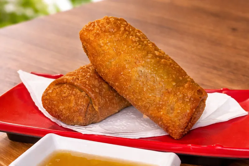 Two golden fried beef and pork lumpia from Wok Dong served on a red tray with dipping sauce