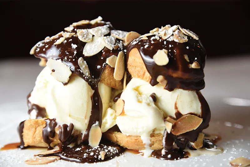 Profiteroles topped with chocolate sauce and toasted almonds over vanilla ice cream at Le Fou Frog in Kansas City.