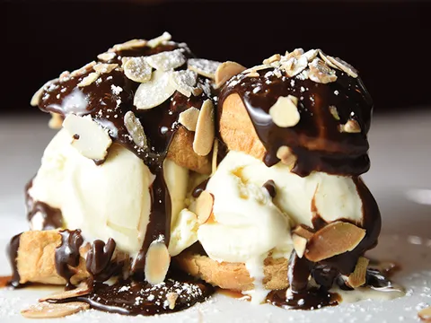 Profiteroles topped with chocolate sauce and toasted almonds over vanilla ice cream at Le Fou Frog in Kansas City.