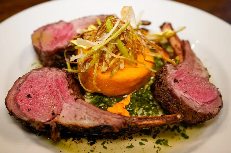 Sliced roasted rack of lamb with sweet potato and herb oil at Triple George Grill