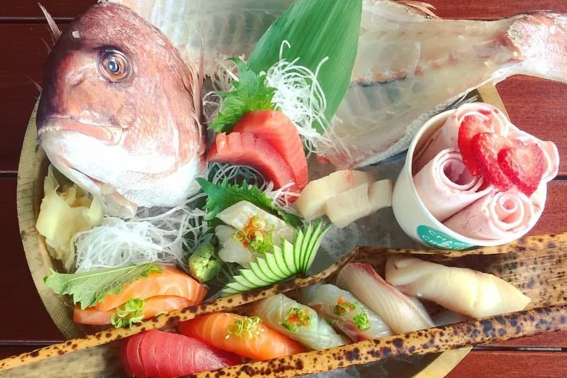 Sushi and sashimi boat at Mizu Izakaya in Denver, with a presentation of whole red snapper, assorted nigiri and sashimi, and a rose-shaped strawberry ice cream