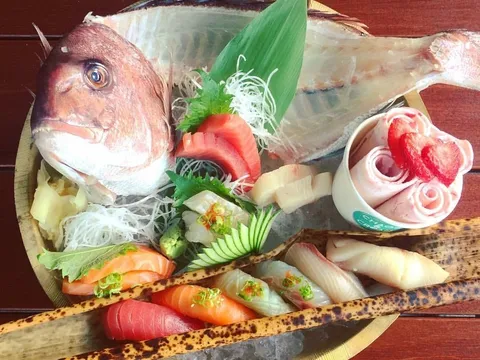 Sushi and sashimi boat at Mizu Izakaya in Denver, with a presentation of whole red snapper, assorted nigiri and sashimi, and a rose-shaped strawberry ice cream