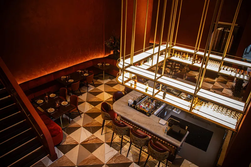 Warmly lit dining room and marble bar at Pataaka in Midtown Atlanta, with deep red walls, gold accents, and a checkered marble floor