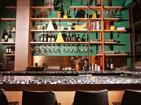 Boia De bar with green shelving, wine bottles and hanging glassware