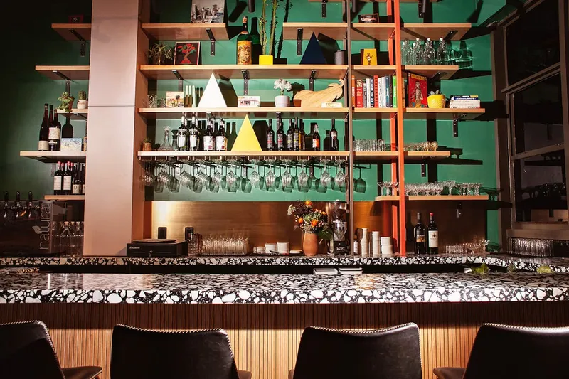 Boia De bar with green shelving, wine bottles and hanging glassware