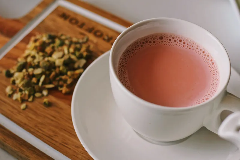 Signature Kashmiri chai (pink tea) topped with nuts, served in a cup at Chai Shai Hillcroft