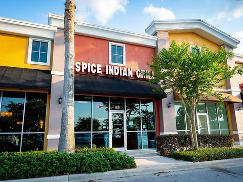 Storefront of Spice Indian Grill in an Orlando plaza, with a black awning and palm trees out front