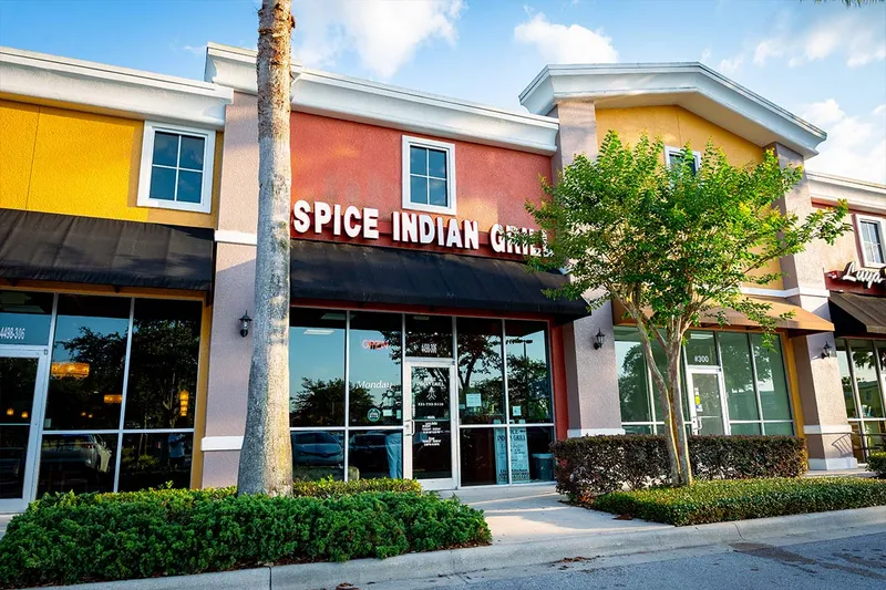 Storefront of Spice Indian Grill in an Orlando plaza, with a black awning and palm trees out front