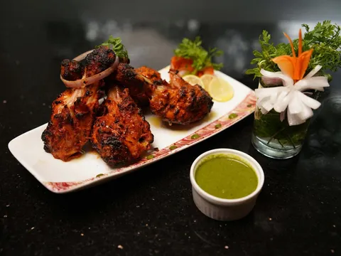 Platter of tandoori chicken with green chutney at Kabab and Curry