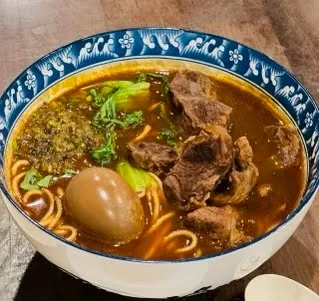 Bowl of beef noodle soup with braised beef, marinated egg and greens at Kung Fu Little Steamed Buns Ramen