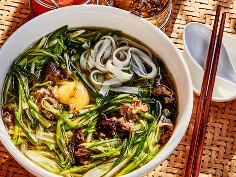 Bowl of Pho Thin Ha Noi beef noodle soup with scallions and egg yolk at Di An Di