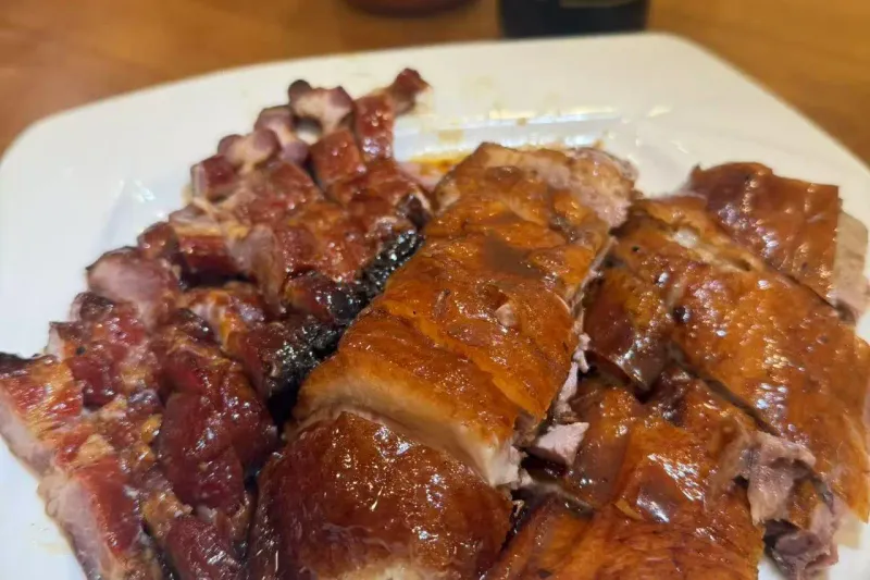 Platter of Cantonese roast duck and barbecued char siu pork at Ting Wong Restaurant in Philadelphia Chinatown, with chili and soy sauce bottles on the table