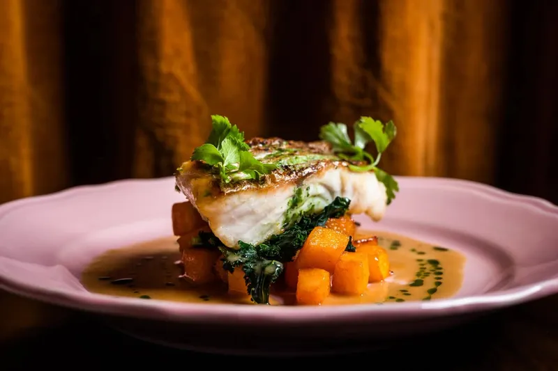 Grilled fish with greens and orange vegetables at Dakar NOLA