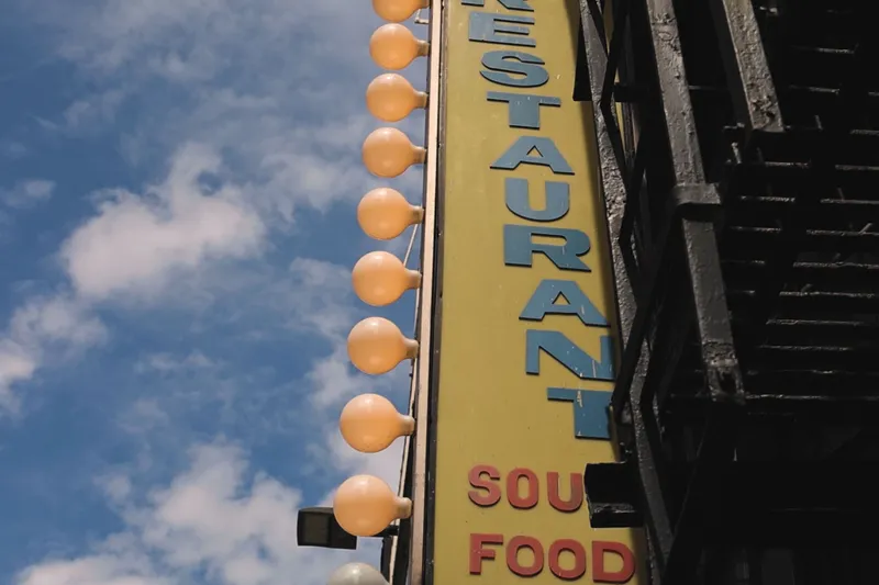 Sylvia's Restaurant's vertical Soul Food marquee sign with round bulbs against a blue Harlem sky