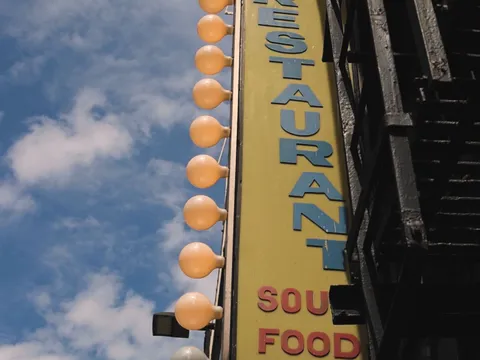 Sylvia's Restaurant's vertical Soul Food marquee sign with round bulbs against a blue Harlem sky