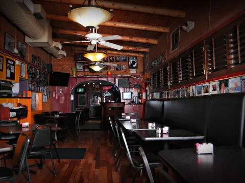 Empty wood-floored dining room at L&J Cafe in El Paso, with black vinyl booths and walls covered in framed photographs
