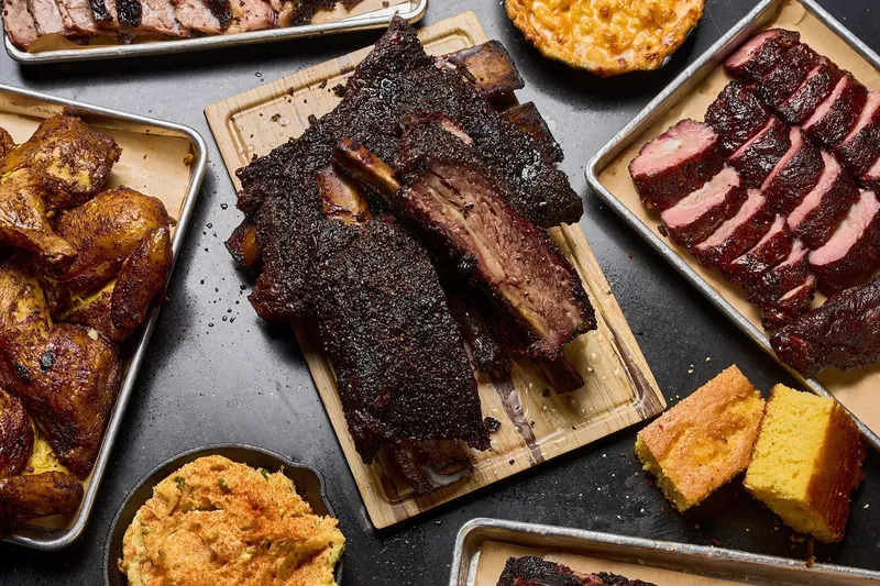 Spread of smoked ribs, brisket, chicken, and cornbread at Bludso's Bar & Que