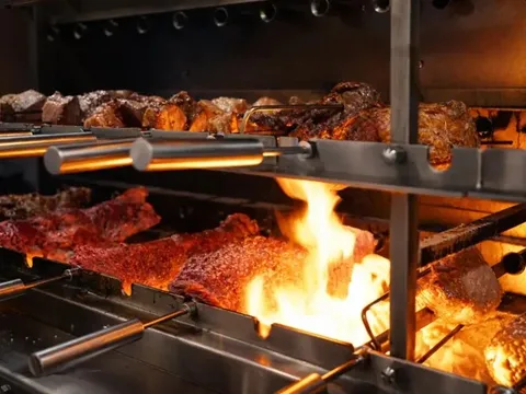 Skewers of churrasco meats roasting over an open flame on the rotisserie grill at Estância Brazilian Steakhouse in Austin