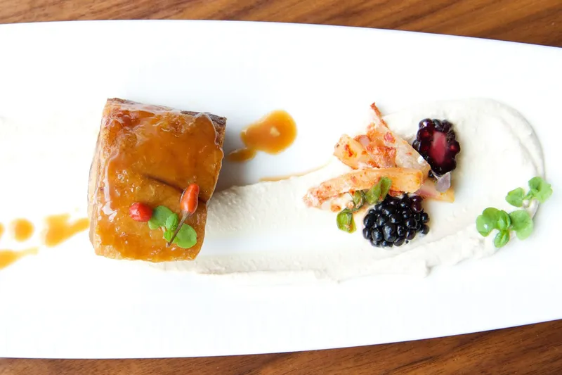 Plated glazed pork belly dish with blackberries and micro herbs at Etch, Nashville