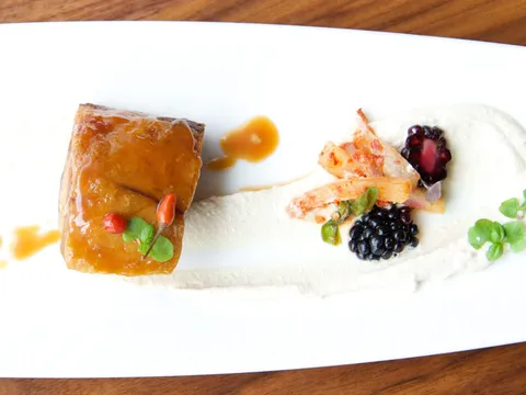 Plated glazed pork belly dish with blackberries and micro herbs at Etch, Nashville