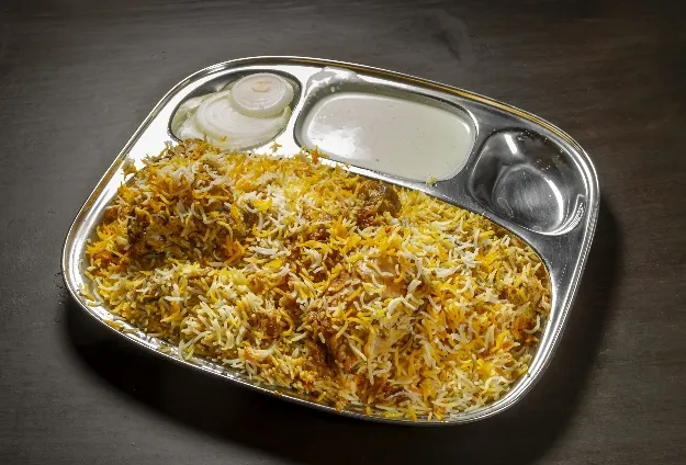 Chicken biryani served on a steel thali plate at Ghareeb Nawaz