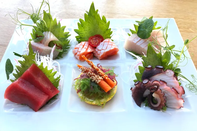 Assorted sashimi platter with tuna, salmon, yellowtail and octopus garnished with shiso and microgreens at Sushi Den in Denver