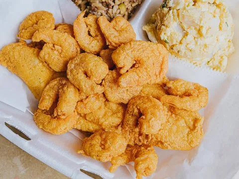 Fried shrimp and catfish platter with dirty rice and potato salad in a takeout container at Li'l Dizzy's Cafe