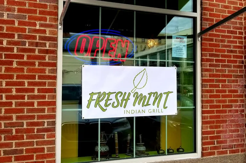 Storefront window of Fresh Mint Indian Grill at 40 High Street, Morgantown, with the restaurant's leaf-logo banner and a red-and-blue neon OPEN sign in the glass