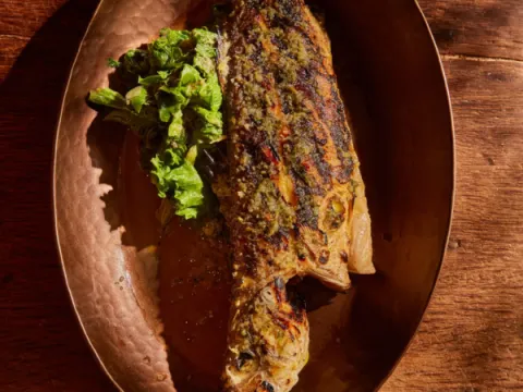 Kokkari Estiatorio's whole grilled fish on a hammered copper platter with a side of greens