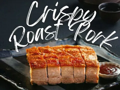 Sliced crispy roast pork belly with dipping sauce on a dark platter at One Roast in Houston