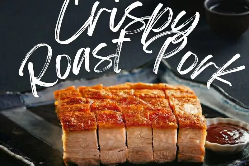 Sliced crispy roast pork belly with dipping sauce on a dark platter at One Roast in Houston