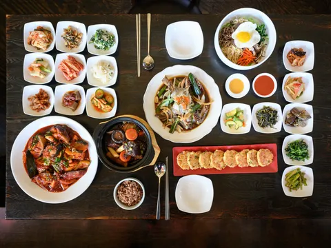 Overhead spread of Soban's Korean dishes with an array of banchan, bibimbap and soy-marinated crab