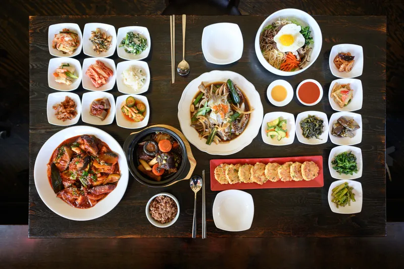 Overhead spread of Soban's Korean dishes with an array of banchan, bibimbap and soy-marinated crab