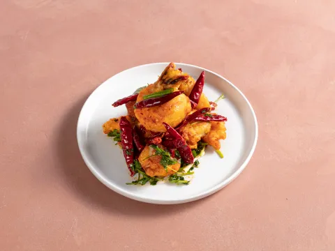 Sichuan-style crispy battered fish tossed with dried red chilies and cilantro on a white plate at Chang Chang