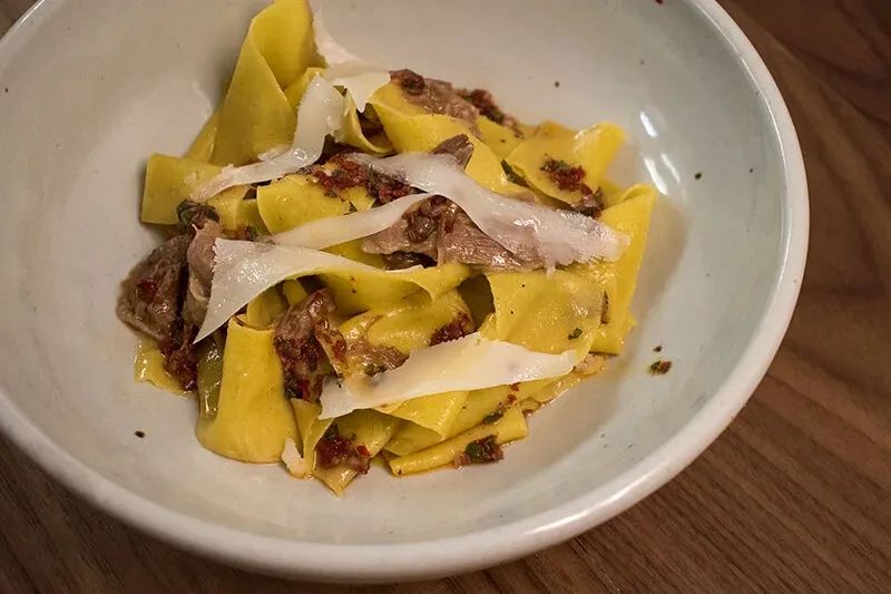 A bowl of pappardelle pasta with shaved cheese at Fairchild