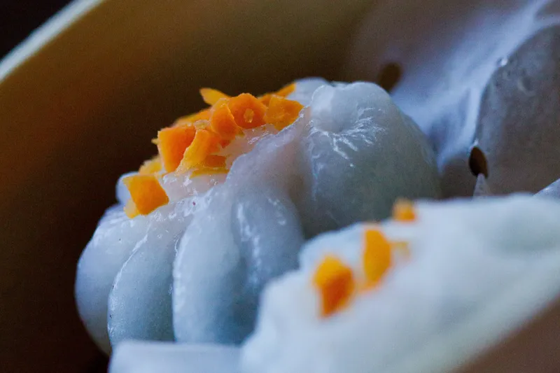 Close-up of a steamed crystal-skin dumpling topped with diced carrot at Empire Chinese Kitchen in Portland, Maine