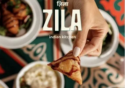 A hand holding a samosa above bowls of curry and sides in a promotional photo for Zila Indian Kitchen in Louisville