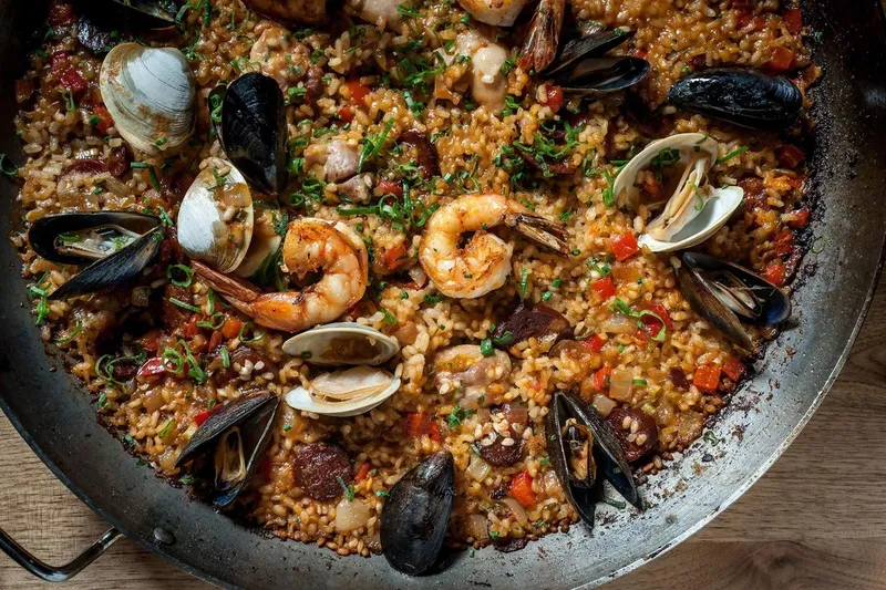Pan of seafood paella with shrimp, clams, mussels and chorizo over saffron rice at Toro in Boston