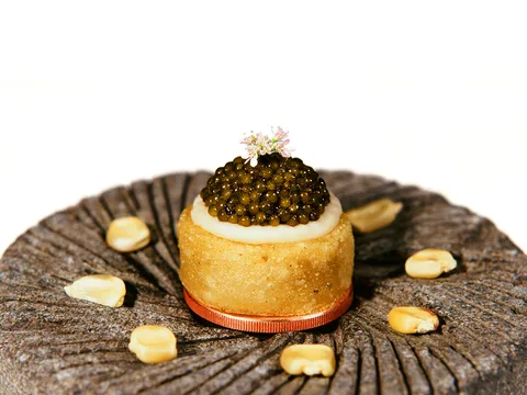 Small masa tart topped with caviar and a flower at Californios