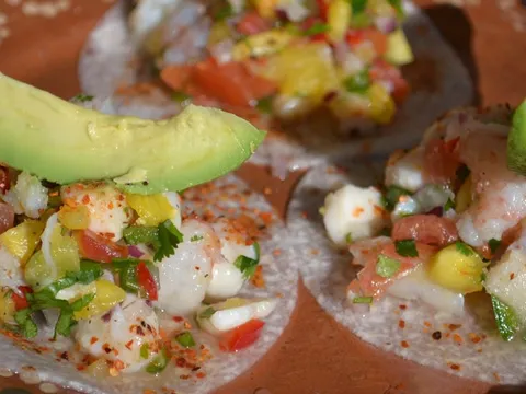 Three ceviche tostadas topped with shrimp, avocado slices, chile powder, and pico de gallo at Machete Tequila + Tacos in Denver