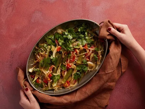 Maydān dish of grilled vegetables and herbs on a red backdrop