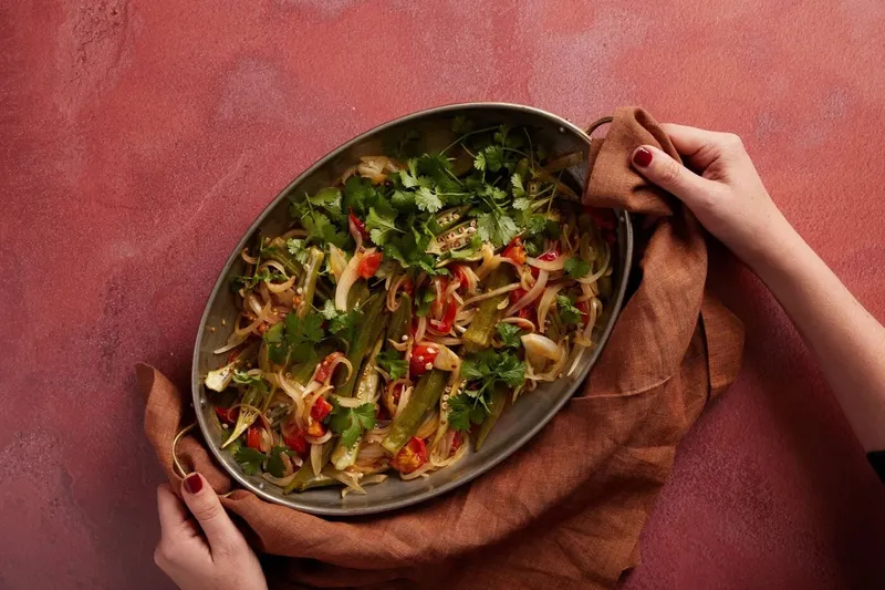 Maydān dish of grilled vegetables and herbs on a red backdrop