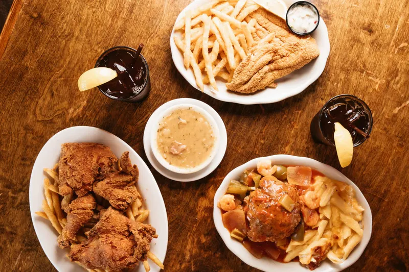 Overhead spread of fried catfish and fries, fried chicken, gumbo and a Creole dish with iced teas at Mandina's Restaurant