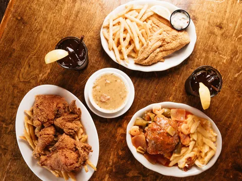 Overhead spread of fried catfish and fries, fried chicken, gumbo and a Creole dish with iced teas at Mandina's Restaurant