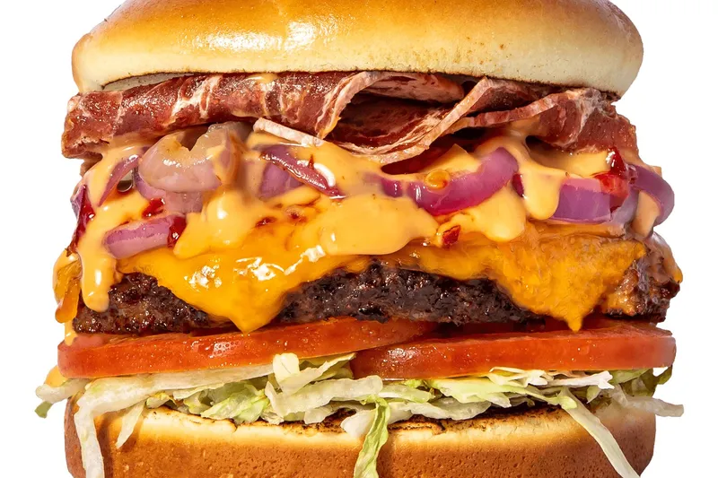Slutty Vegan One Night Stand plant-based burger with vegan bacon, vegan cheese, onions, tomato, and lettuce on a bun