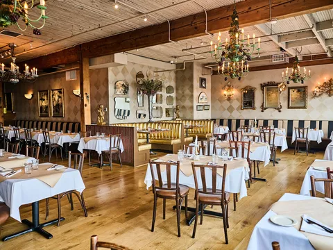 Bright dining room at The Pink Door with white tablecloths and chandeliers